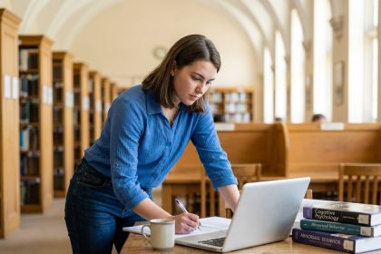 Jeune femme concentr&eacute;e &agrave; &eacute;tudier dans une biblioth&egrave;que universitaire